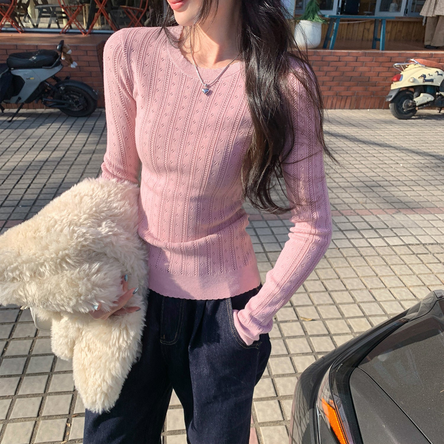 Woman wearing Hollow-Out Round Neck Long Sleeve Knit Top in a stylish setting