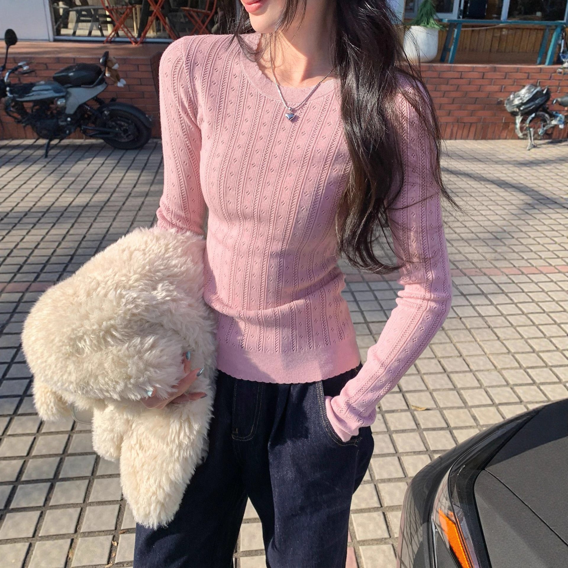 Woman wearing Hollow-Out Round Neck Long Sleeve Knit Top in a stylish setting