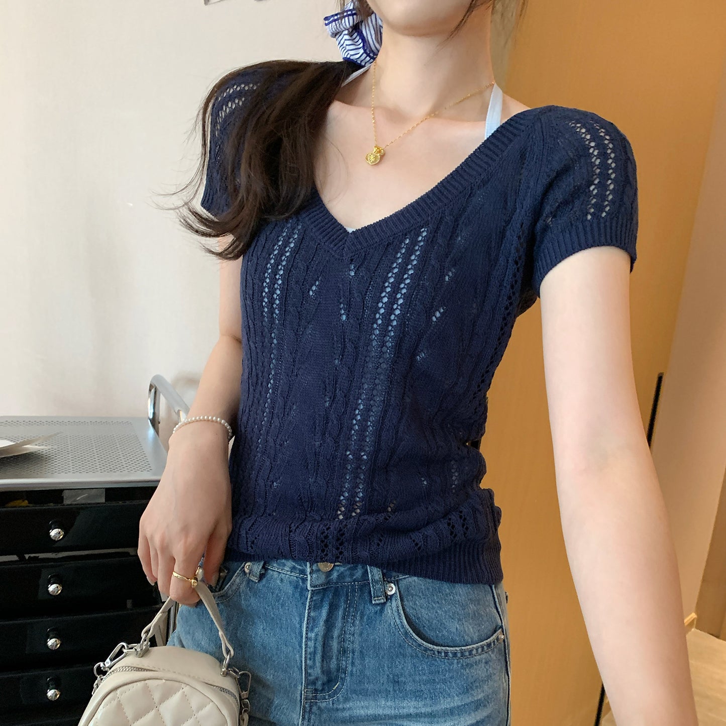 Woman wearing V-Neck Hollow Knit Top in a stylish outdoor setting